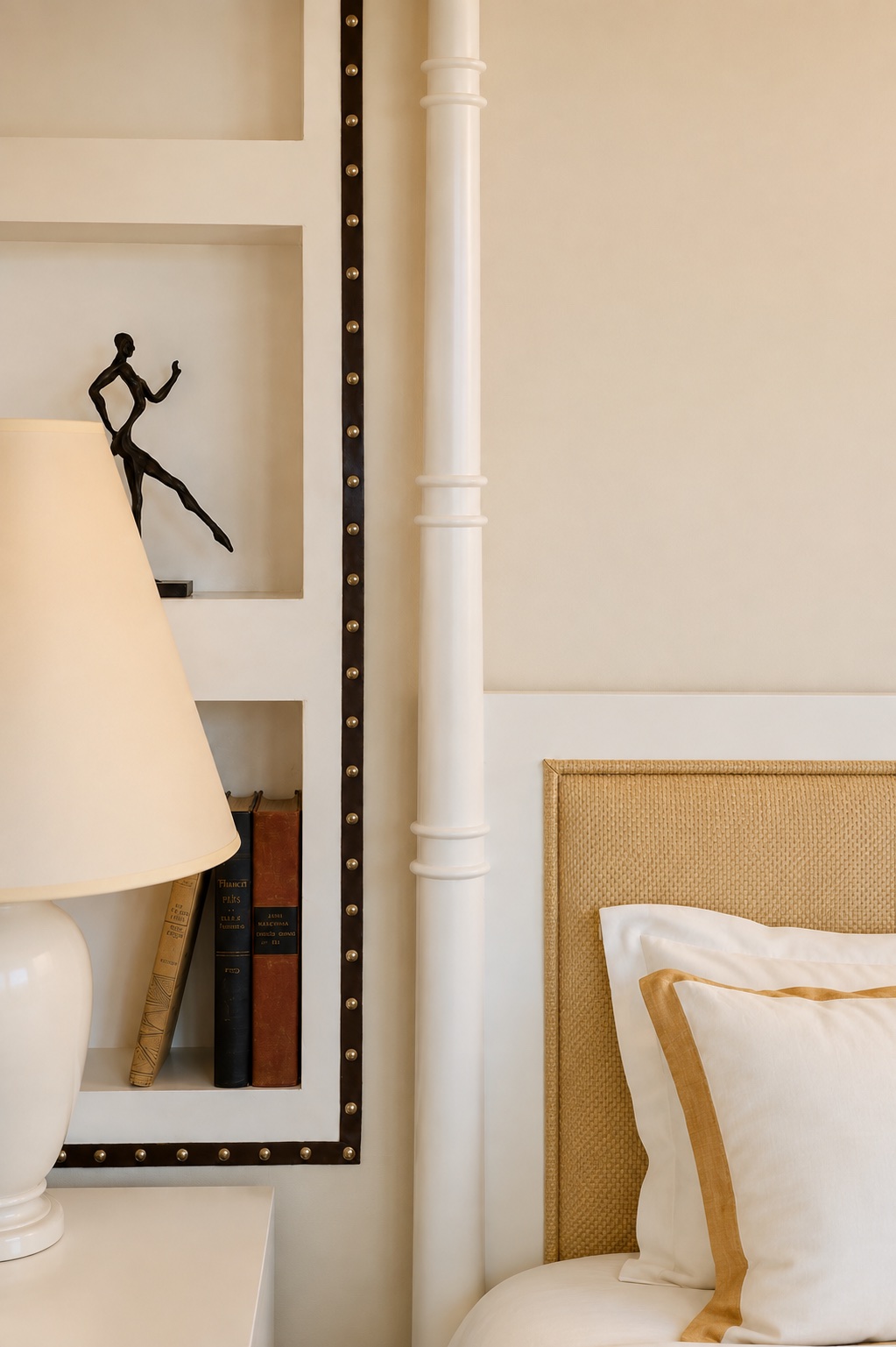 The Betsy Hotel — bedside detail with a studded niche, bronze figure, and cane headboard