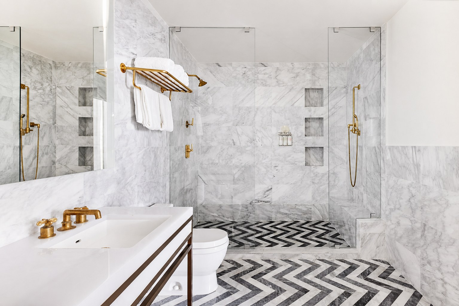 The Carlton Hotel — the penthouse marble bathroom with a chevron floor and brass fittings