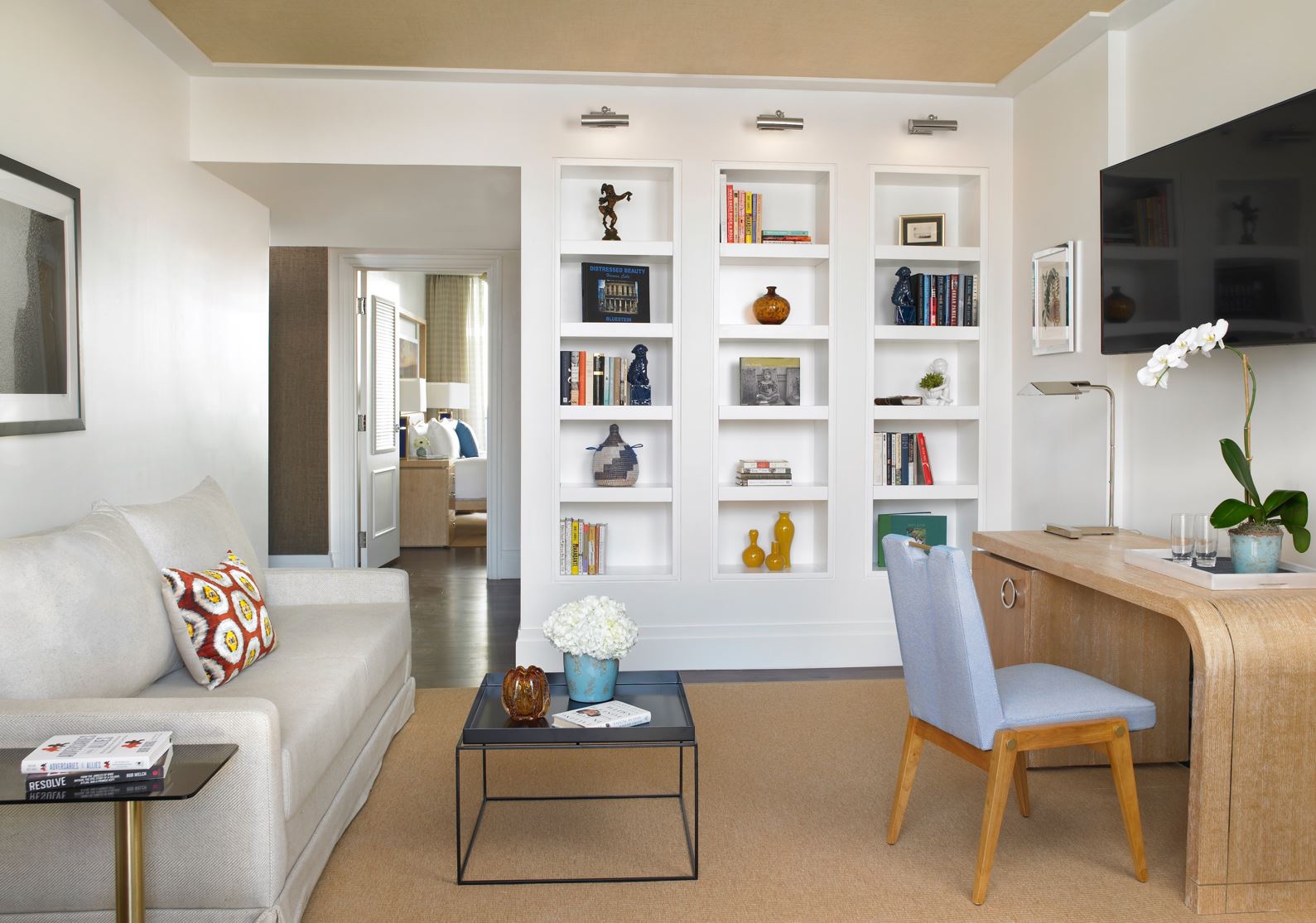 The Carlton Hotel — a suite living room with white built-in shelving and a bleached-wood desk